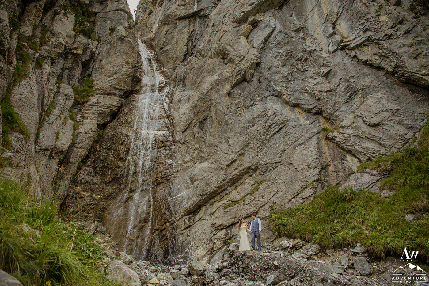 Adventurous elopement couple exploring a waterfall at oeschinensee