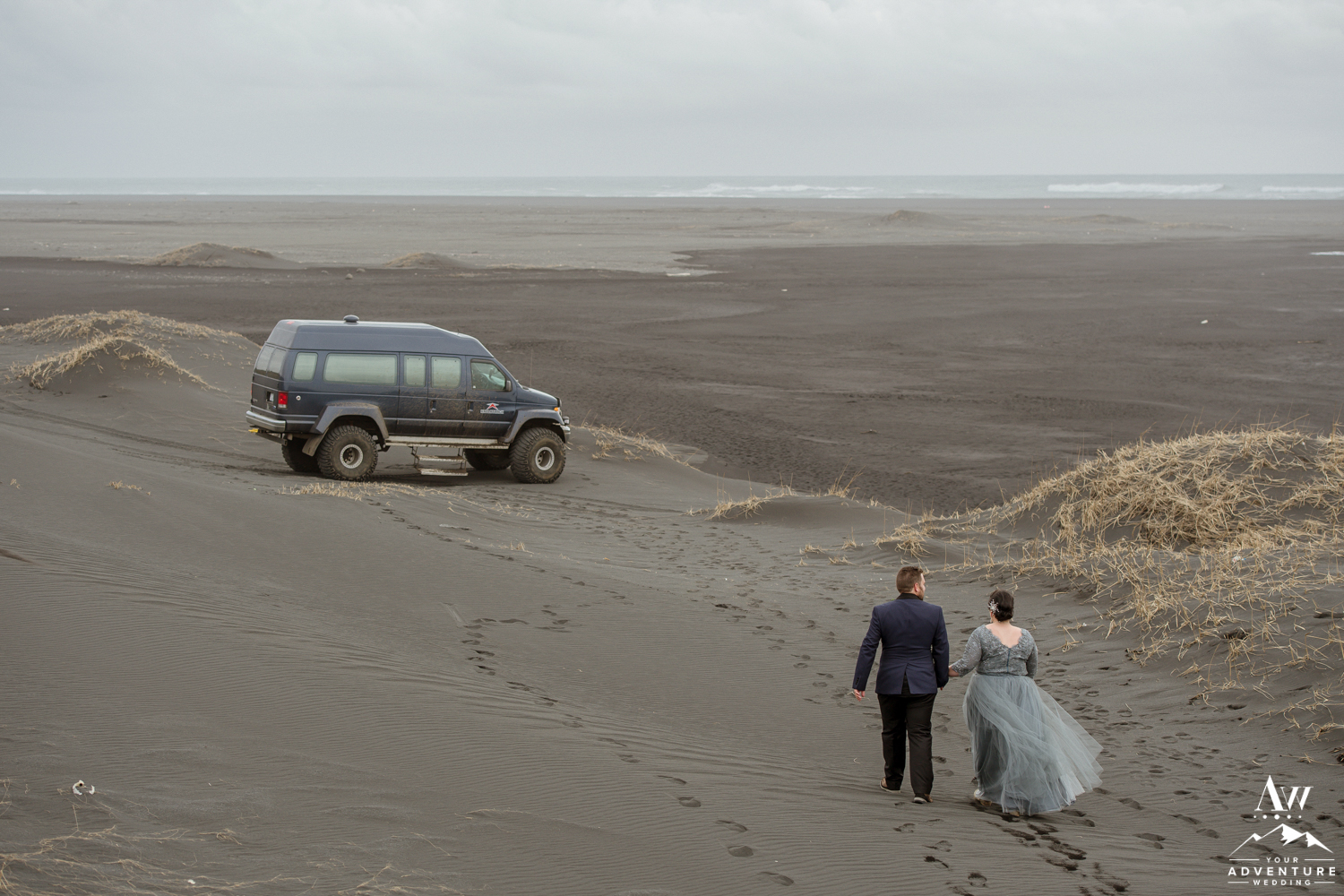 Adventurous Wedding Couple walking towards super jeep on black beach