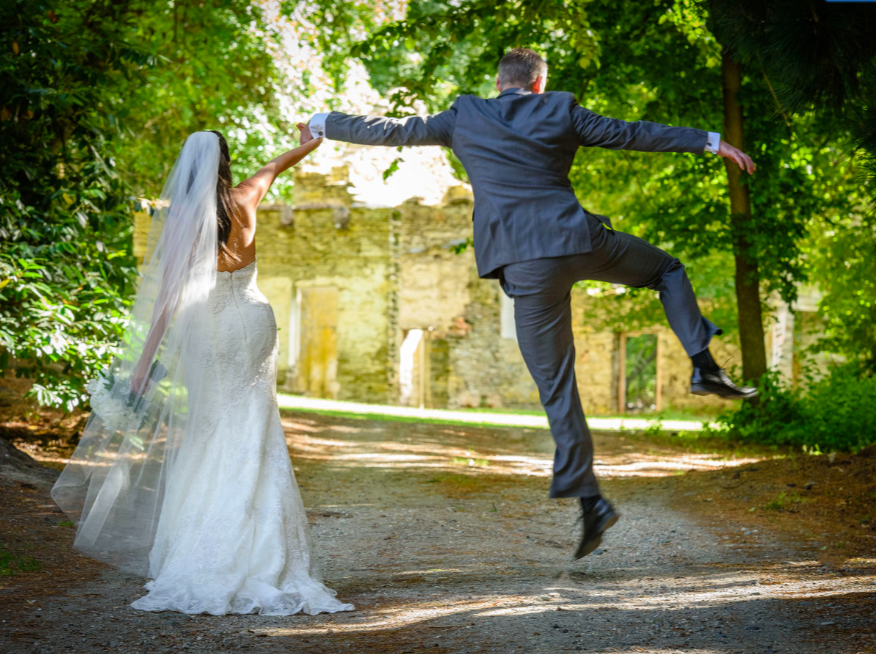 Groom and bride jumping in the air holding hands