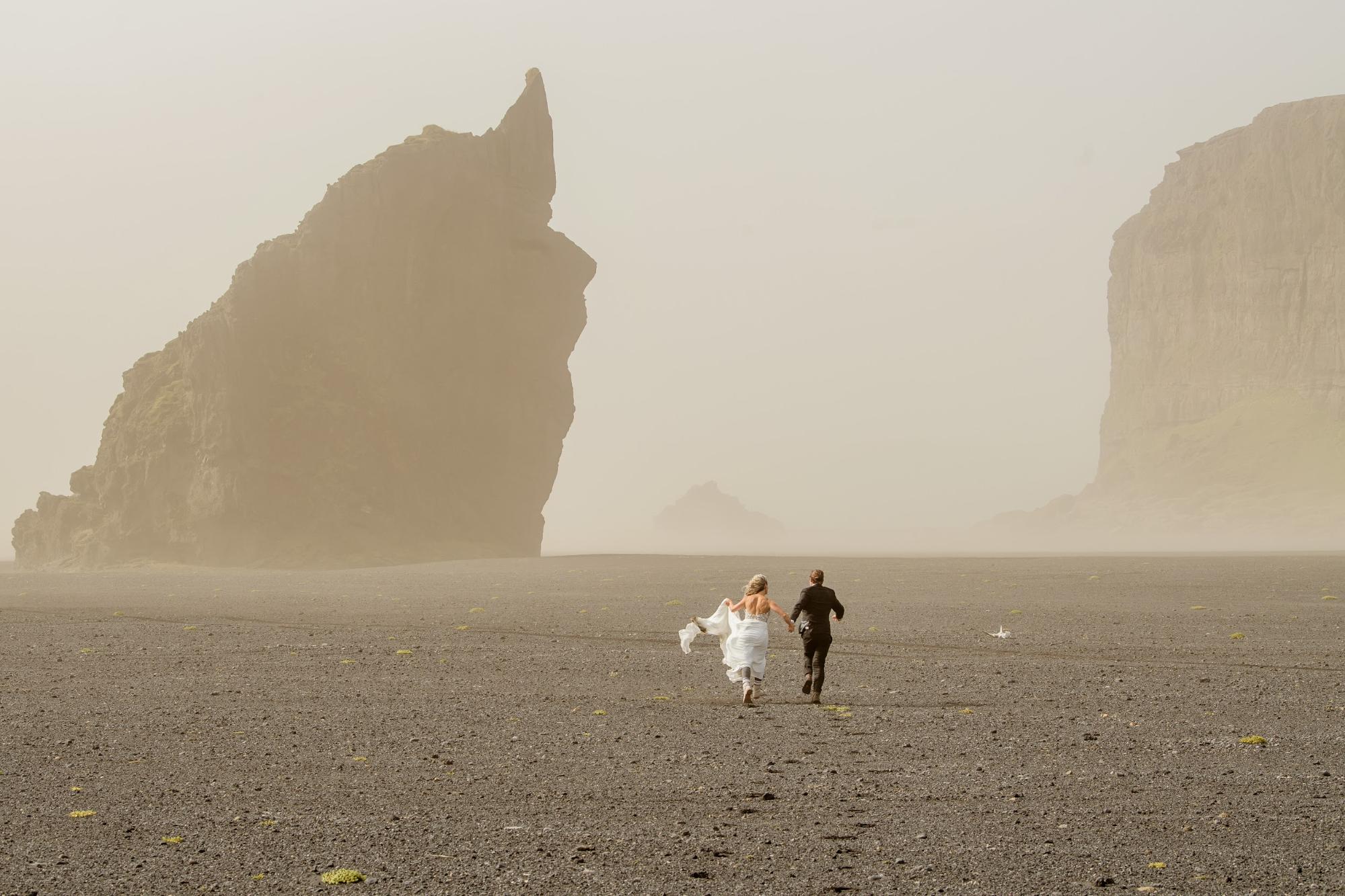 Bride with flowy dress running hand-in-hand with groom into the distance