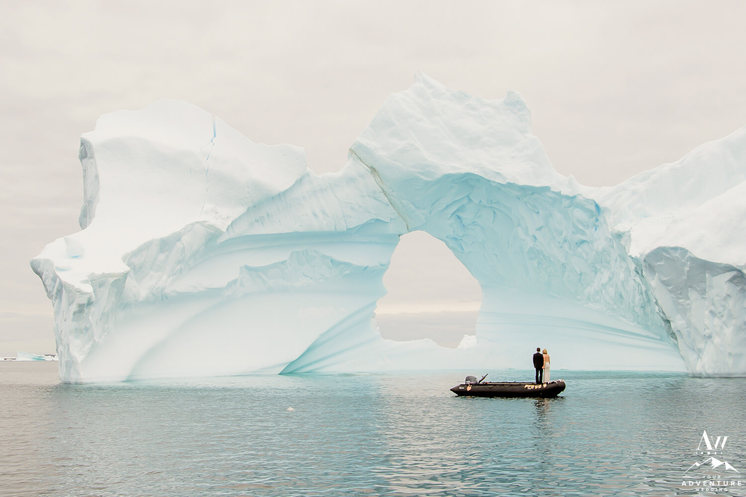 Couple standing in a zodiac in front of icebergs